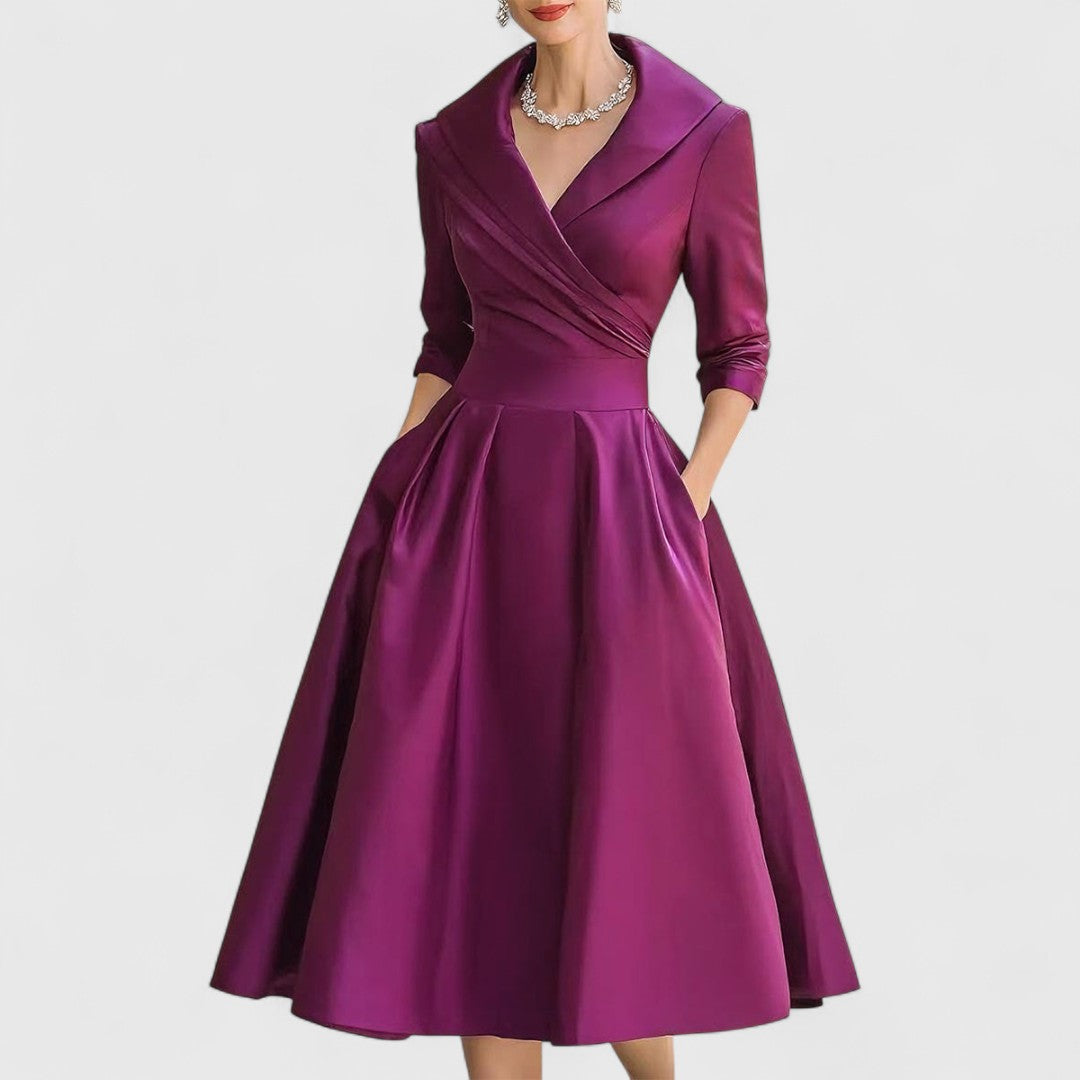 Rich purple version of the satin midi dress with shawl collar, fitted waistband and full skirt, worn with a crystal necklace. 5