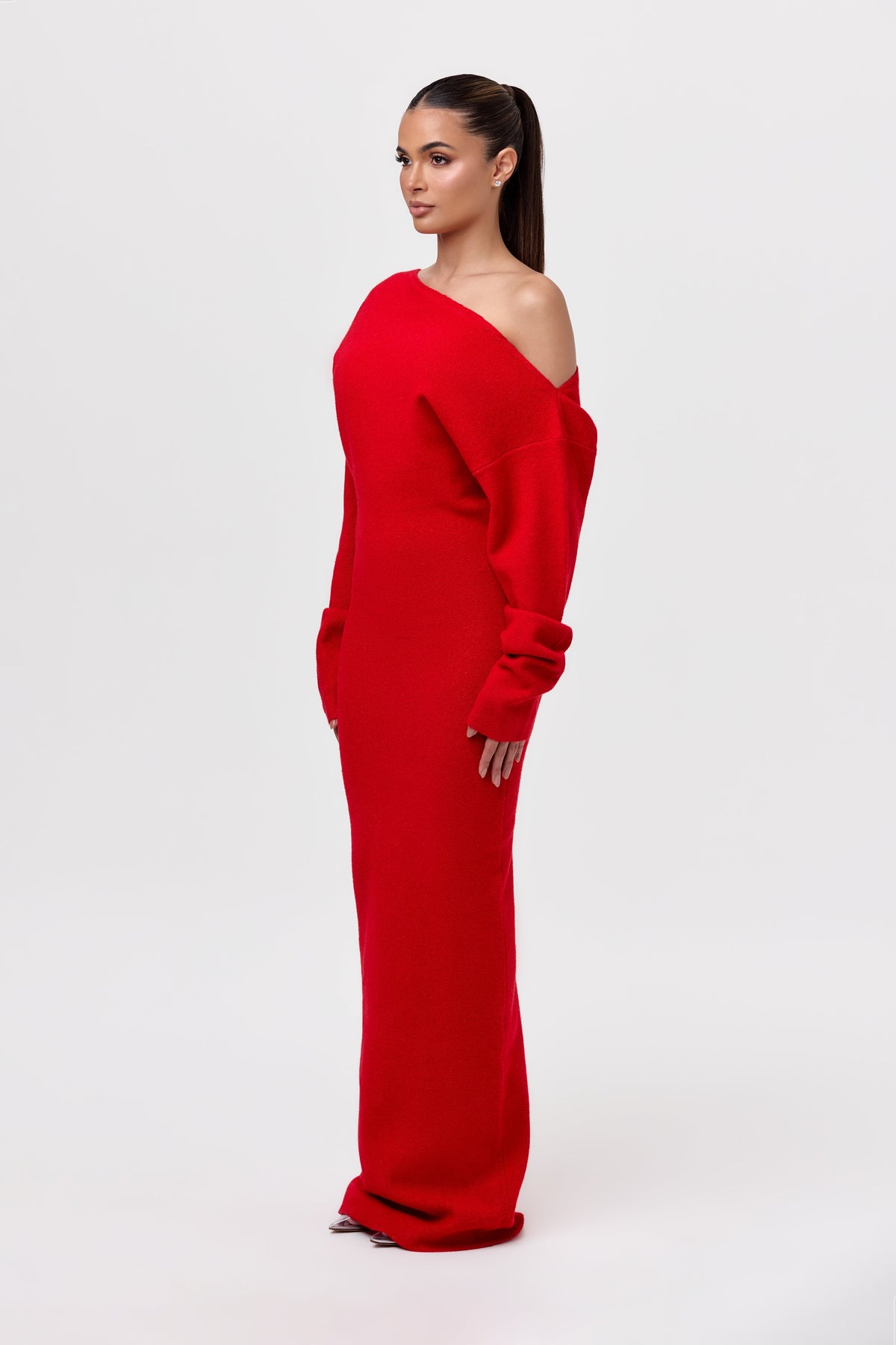 Side view of the red knit maxi dress, showing the asymmetric bare-shoulder neckline and gathered cuffs on the long sleeves. 22