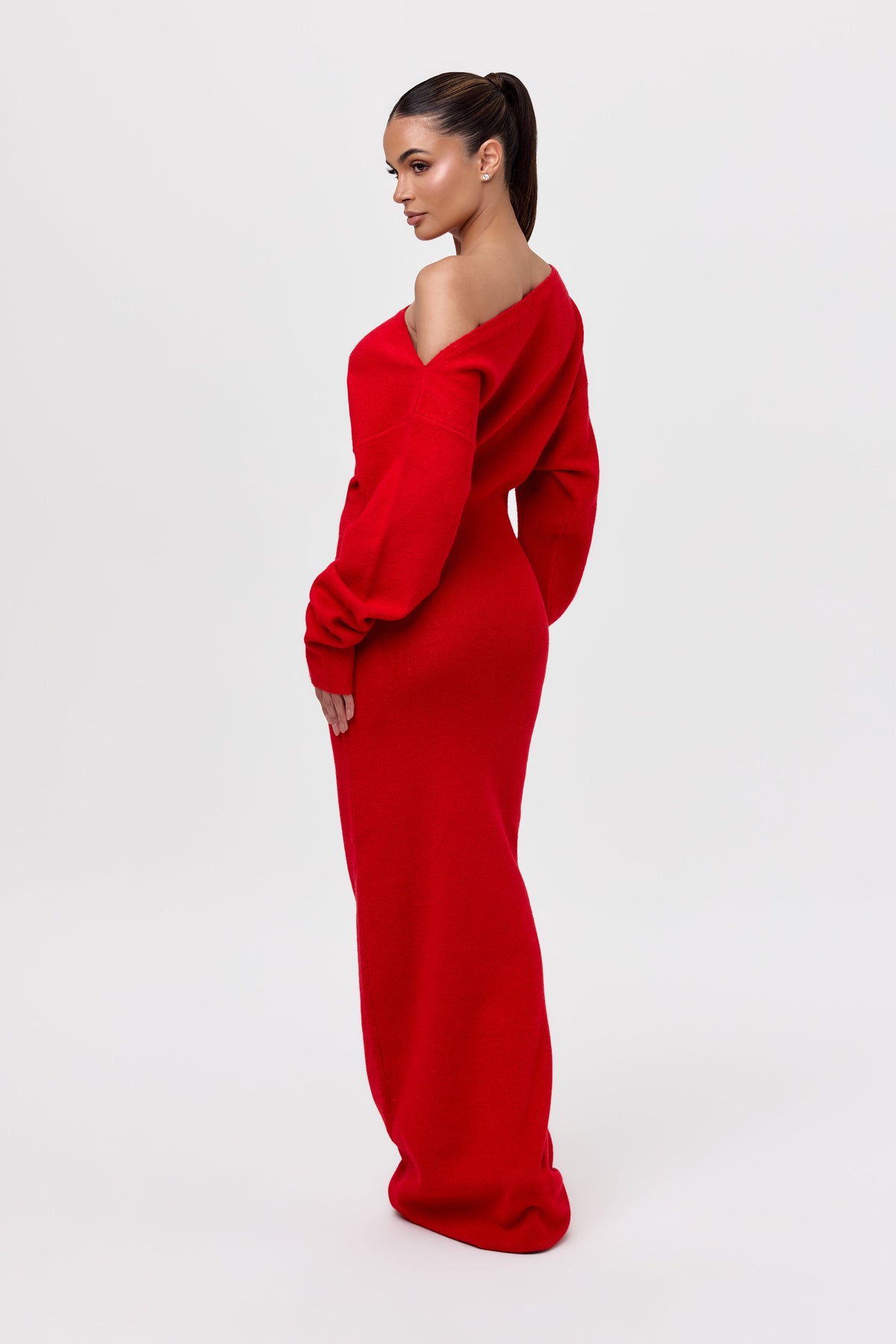Back three-quarter view of the red knit dress, showing the slanted neckline, the seam across the shoulders and the fitted skirt. 23