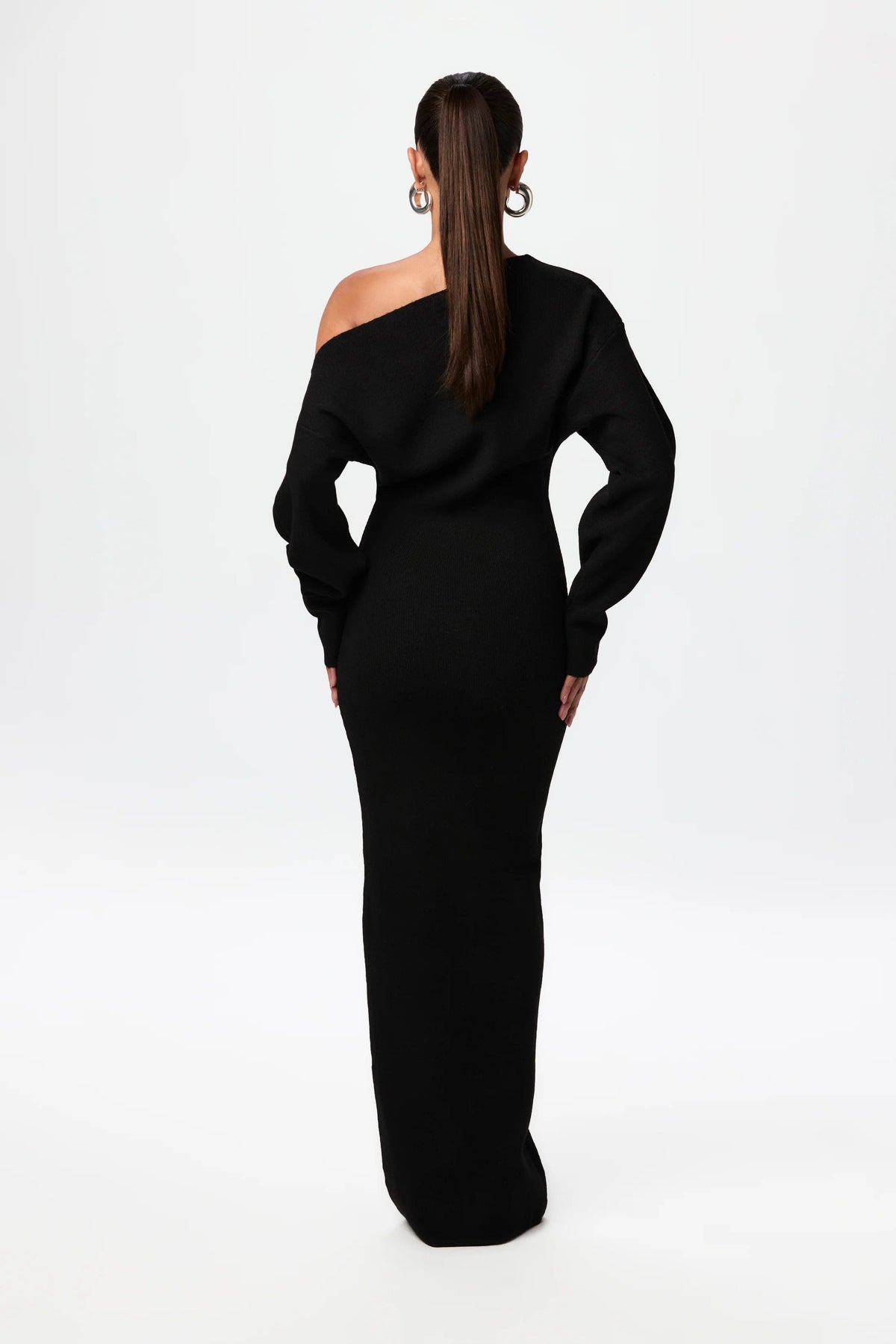 Back view of the black knit maxi dress, showing the asymmetric neckline, long sleeves and fitted skirt. 3