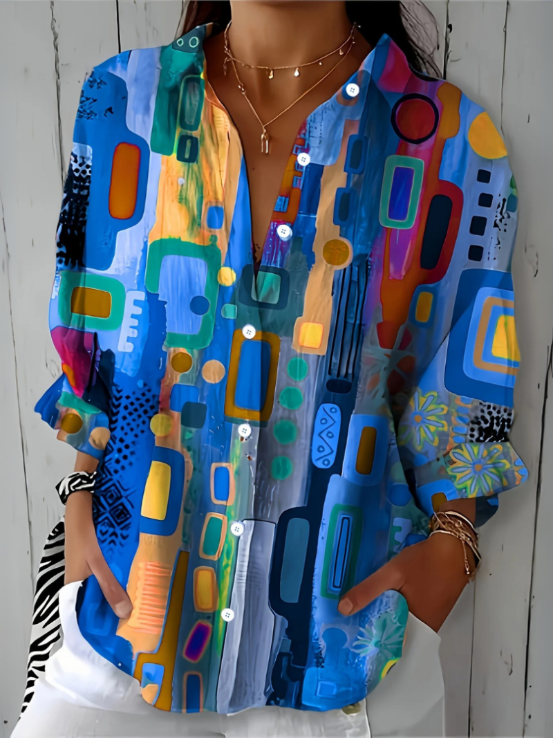 Close-up crop of the blue abstract-print blouse on a model, showing the buttons, open neckline and relaxed sleeves in the blue colourway. 6