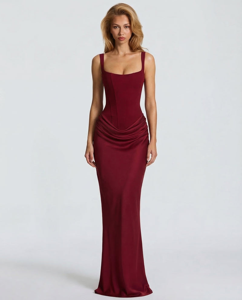 Front view of the deep red satin-look dress on a model, with a corset bodice, wide straps and a draped hip. 9