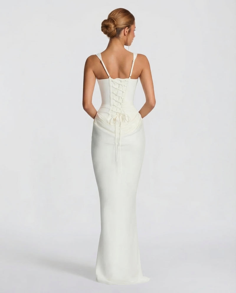 Back view of the ivory dress showing thin adjustable straps, a lace-up corset back and long ties over the draped skirt. 6