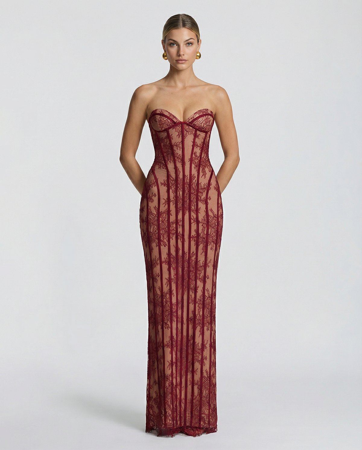 Model facing the camera in the burgundy lace maxi dress, hands behind her back, showing the sweetheart bustier and vertical boning. 1