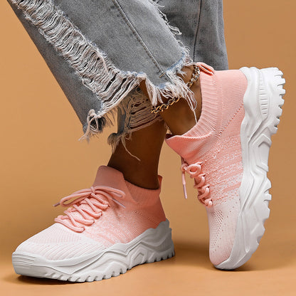 Pink and white knit lace-up sneakers with chunky white soles, worn with frayed grey jeans and a gold chain anklet. 6