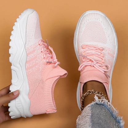 Top-down view of pink and white gradient knit sneakers with chunky white soles, one held up and one worn. 4