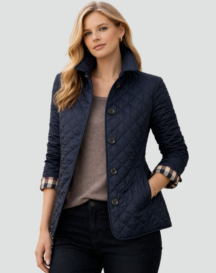 Model wearing the navy quilted jacket with a check cuff lining, worn open over a taupe top and dark jeans, hand in pocket. 5