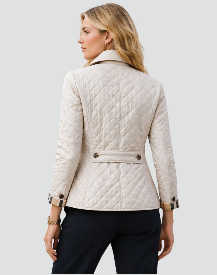 Back view of the cream quilted jacket on a model, showing the diamond stitching, centre seam, buttoned back strap and check cuffs. 8