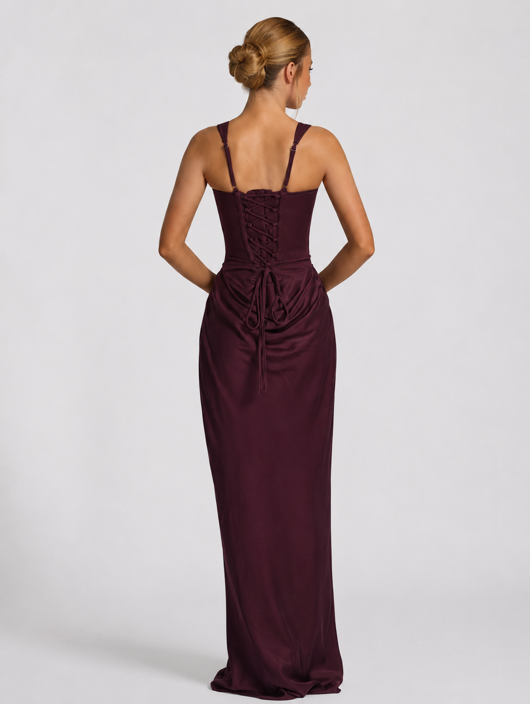 Back view of the plum dress showing adjustable straps, a lace-up corset back with long ties and the ruched skirt below. 14
