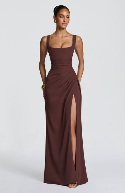 Model wearing the brown square-neck maxi dress, facing forward with ruched waist, high side slit and gold jewellery. 1