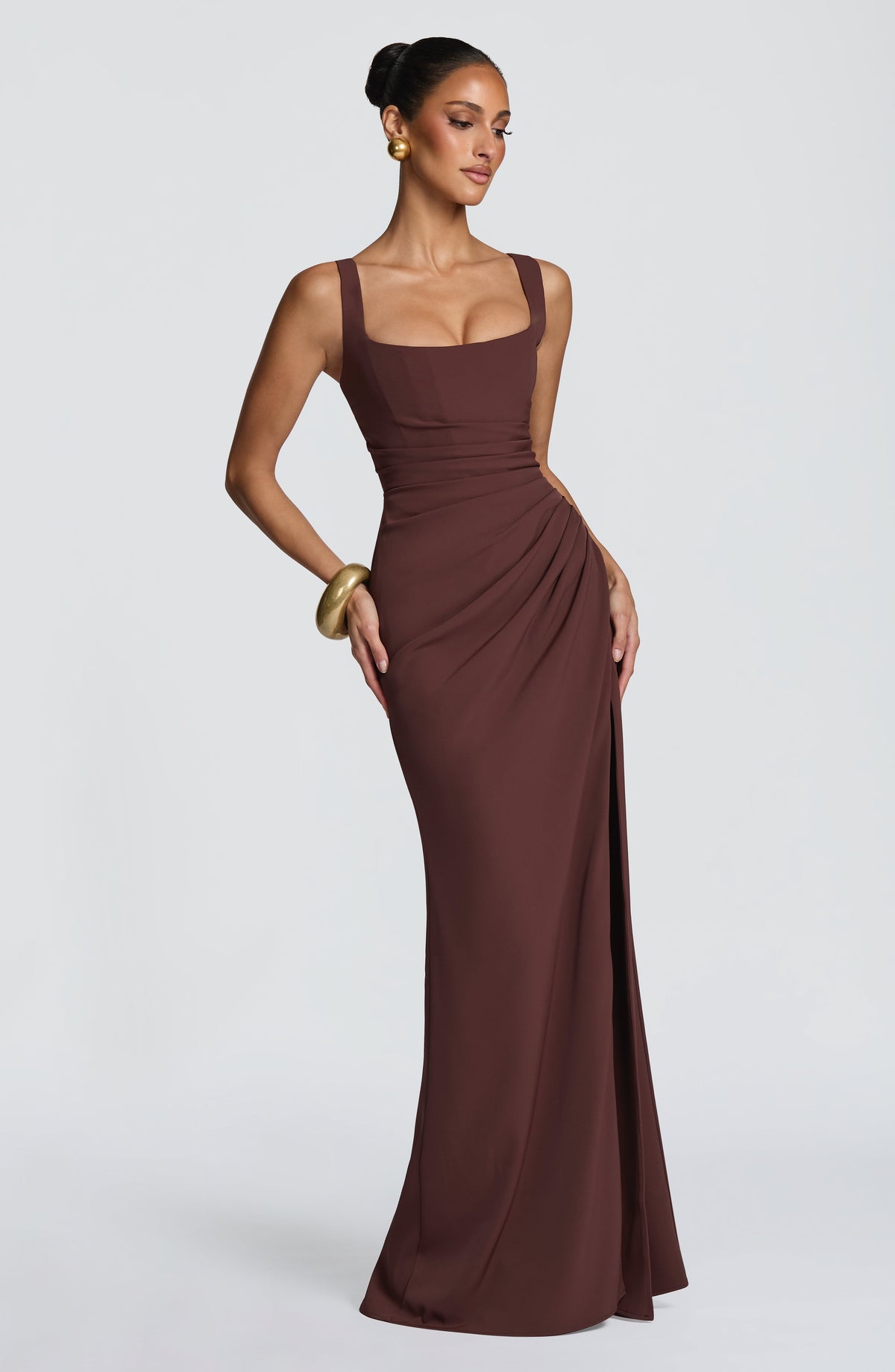 Angled side view of the brown dress with one hand resting on the hip, showing the ruching and slit. 5