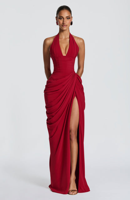 Front view of the dress in deep red, worn with gem-style earrings, showing the pleated halter bodice and draped slit skirt. 16