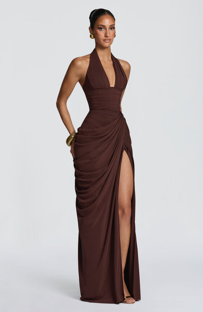 Three-quarter view of the brown dress on a model, hand resting at the hip, with the thigh split opening. 27
