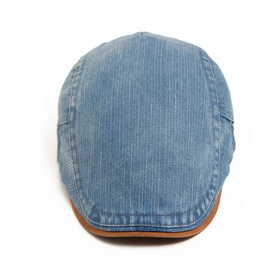 Front view of the blue denim flat cap with fine vertical pinstripe texture and a tan peak edge. 11