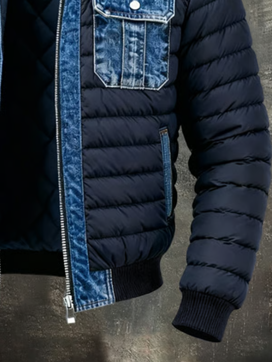 Lower front and sleeve of the open jacket, showing the padded navy body, denim side pocket, ribbed hem and cuff. 5
