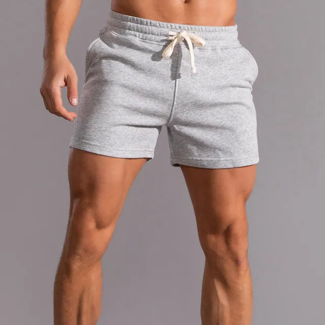 Light grey marl shorts with a cream drawstring and elasticated waist, modelled from the front with one hand relaxed. 4
