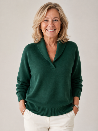 Full-length front view of a smiling woman in the dark green jumper, hands in the pockets of white trousers. 9