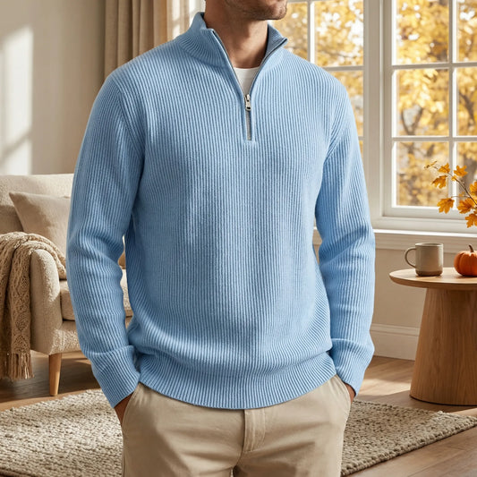 Model in the light blue ribbed half-zip pullover with beige chinos, hands in pockets, standing in a cosy autumn living room. 2