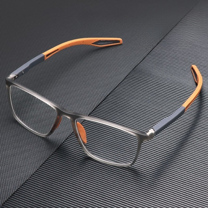 Translucent grey glasses with orange arm tips, shown from a high angle on a dark ridged surface. 4