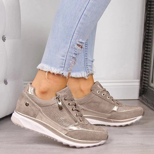 Side view of a model wearing the champagne-beige suede-effect trainers with side zip and studded panel, with ripped light-blue jeans. 1