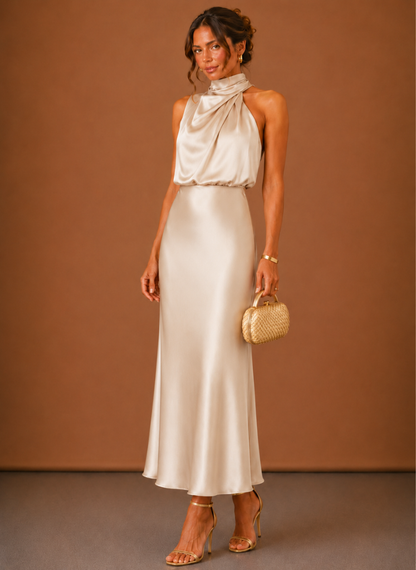 Full-length front view of the dress in a pale champagne satin, styled with gold heels and a woven clutch. 4
