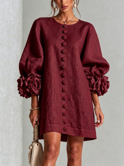Deep burgundy dress worn by a model, front view, with a row of flower buttons down the centre and rosette-trimmed puffed sleeves. 38