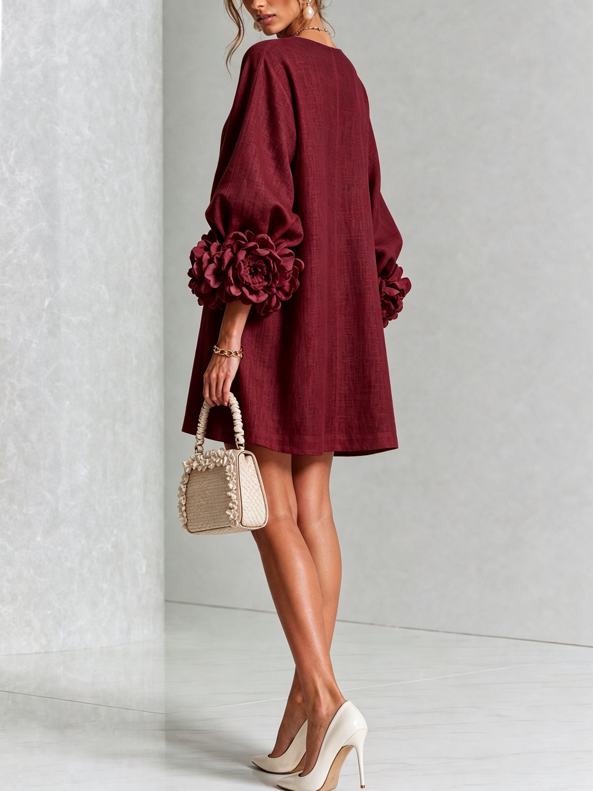 Burgundy dress from the back on a model looking over her shoulder, with a plain loose back and big rosettes on the sleeves. 40