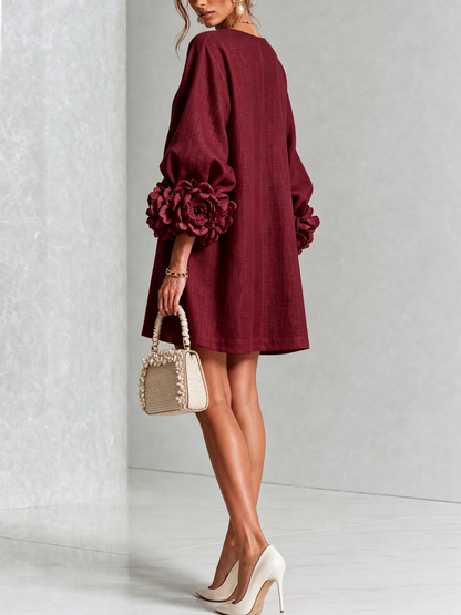 Burgundy dress from the back on a model looking over her shoulder, with a plain loose back and big rosettes on the sleeves. 40