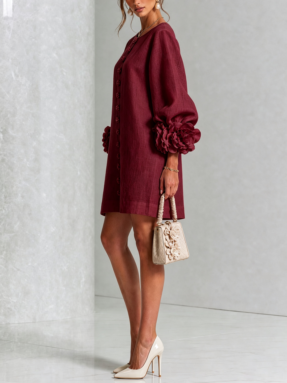 Burgundy dress in side view on a model holding a cream floral handbag, showing the balloon sleeve with its rosette cuff. 39