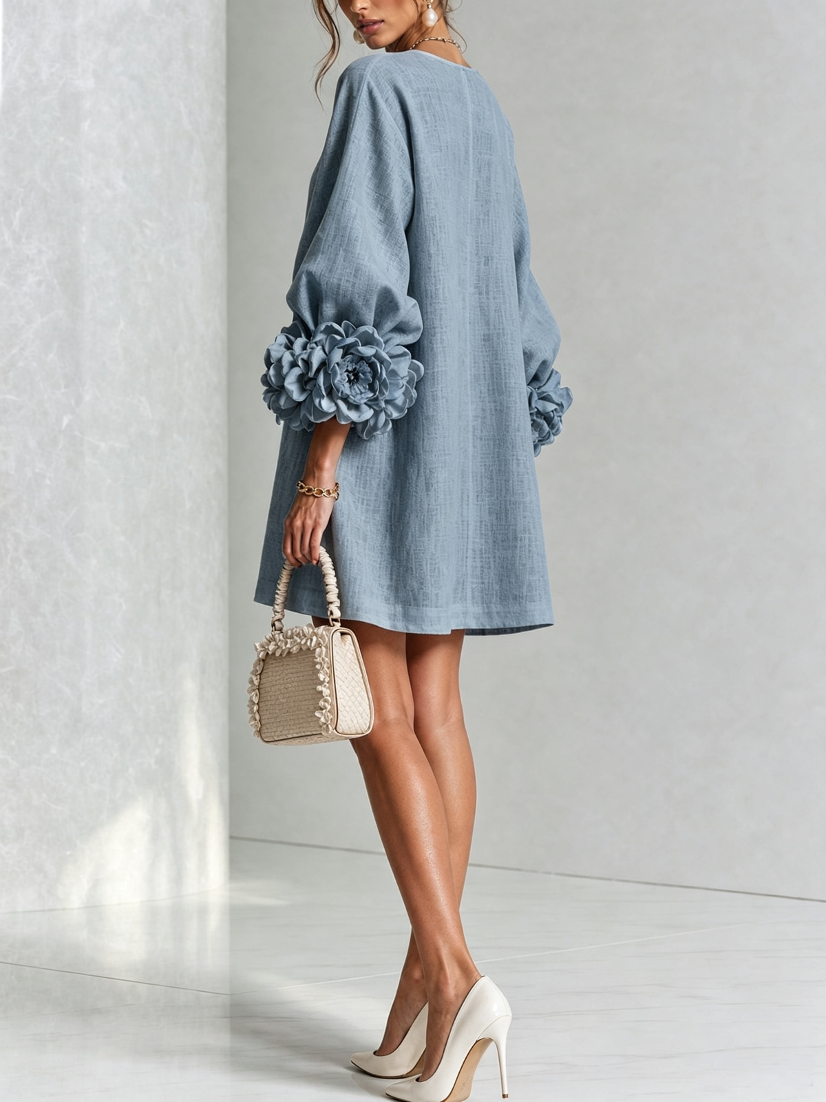 Back view of the light blue dress on a model looking over her shoulder, with large rosettes on the sleeves. 43
