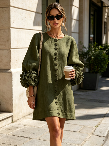 Olive green version worn outdoors by a model with a woven shoulder bag, showing the oversized rosette cuffs and flower buttons. 2