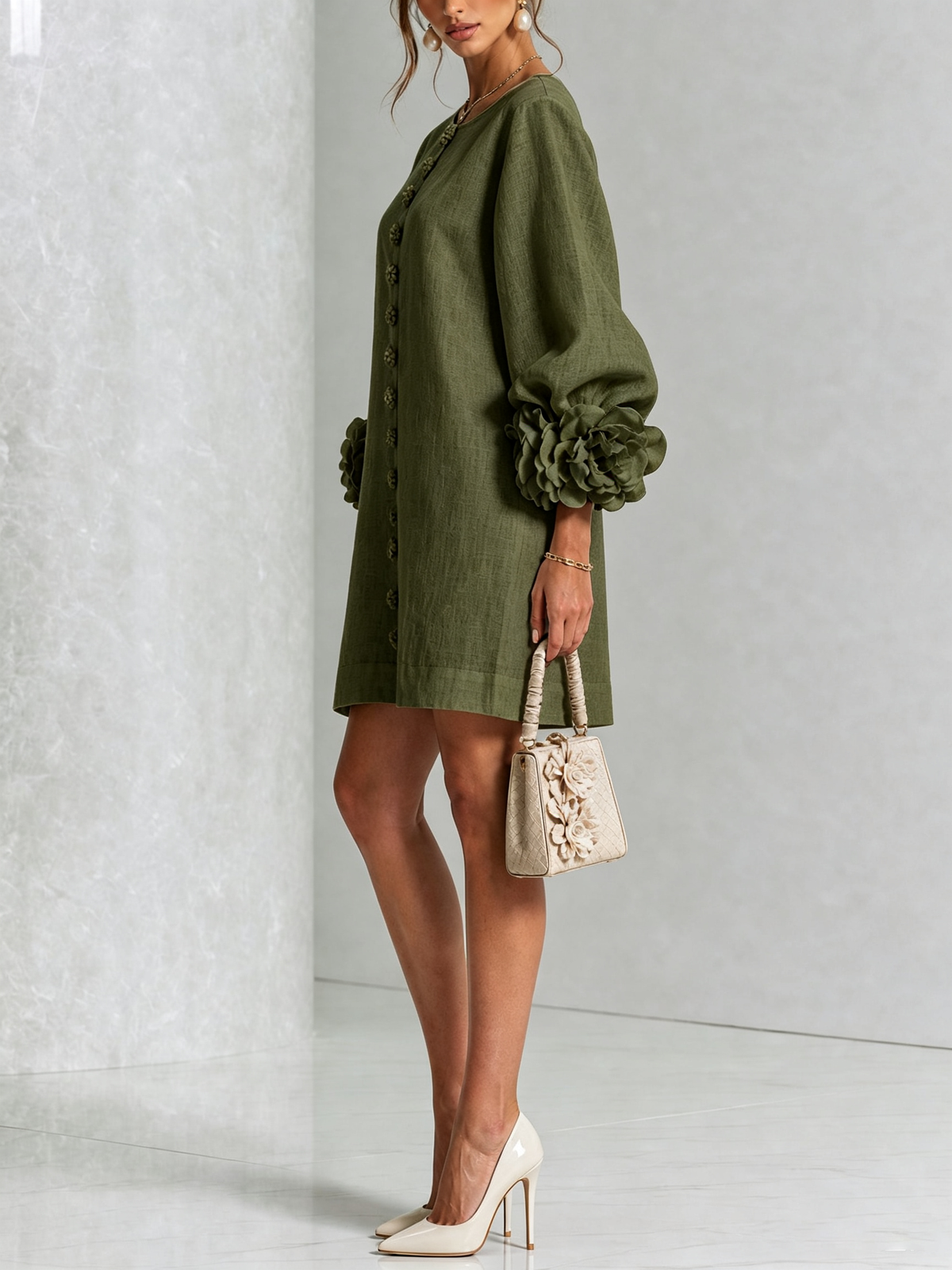 Side view of the olive green dress in a studio, showing the balloon sleeve with a rosette cuff and a small flower-trimmed handbag. 17