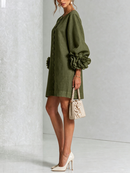 Side view of the olive green dress in a studio, showing the balloon sleeve with a rosette cuff and a small flower-trimmed handbag. 17