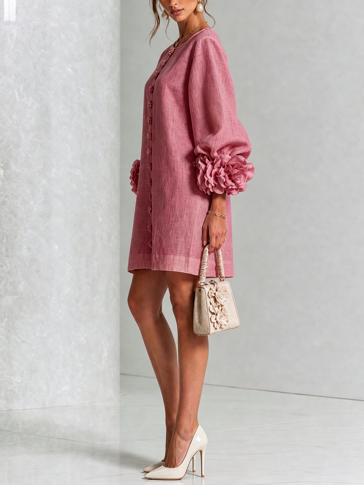 Side view of the dusky pink dress worn with cream heels and a small cream handbag, showing the rosette cuffs. 45