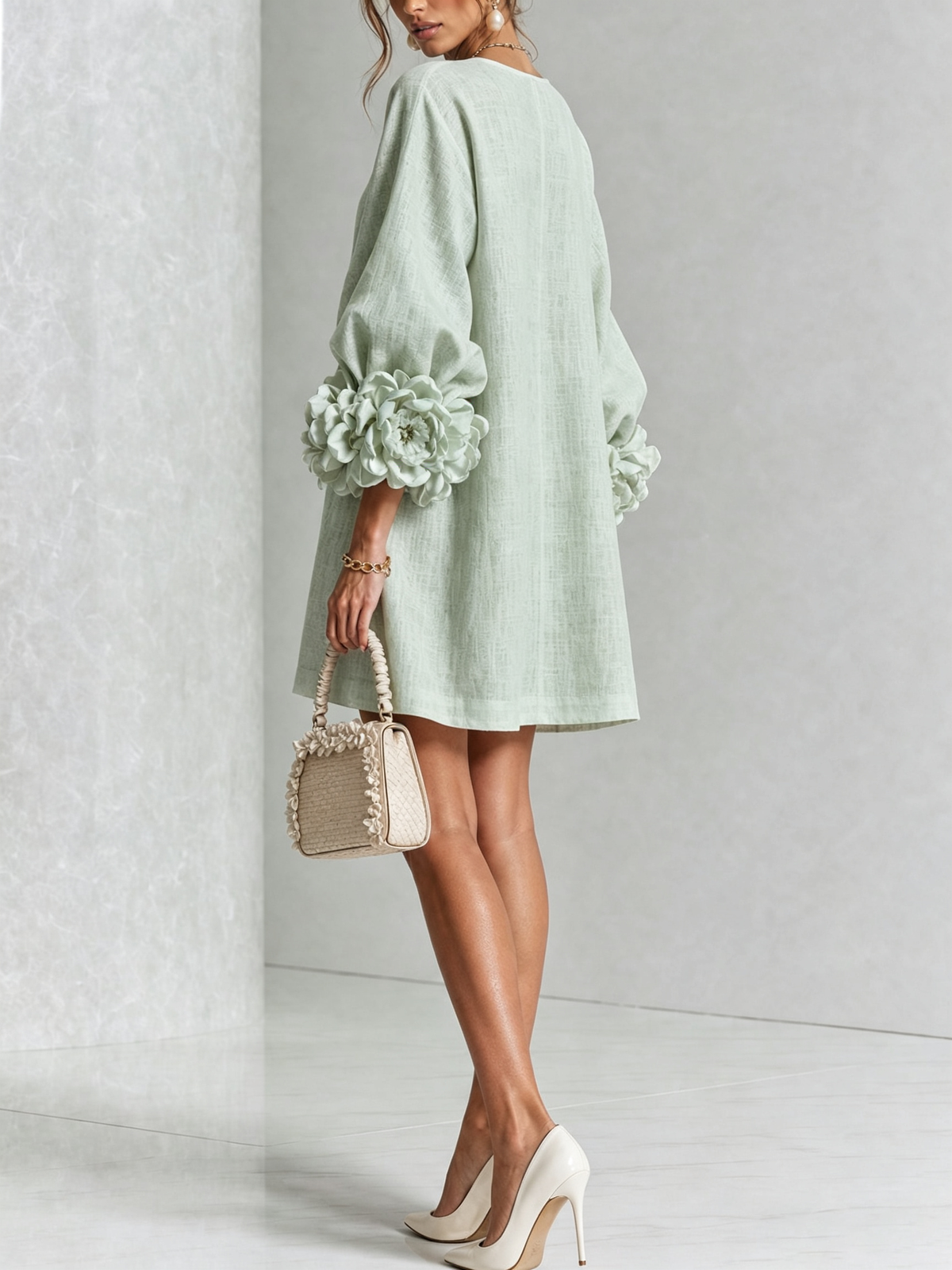 Sage green dress from behind on a model glancing back, showing the plain back and oversized rosettes on the sleeves. 37