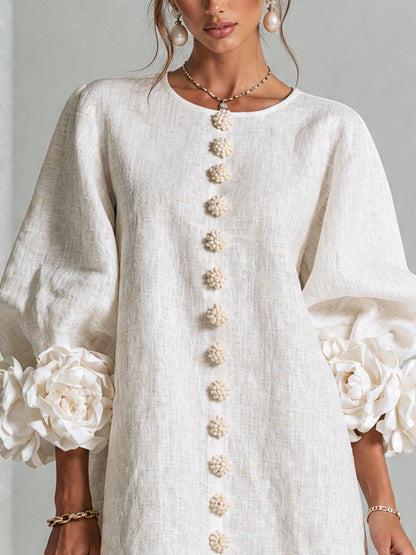 Close-up of the cream dress bodice, showing the round neckline, flower-shaped buttons and large rosette cuffs on puffed sleeves. 15