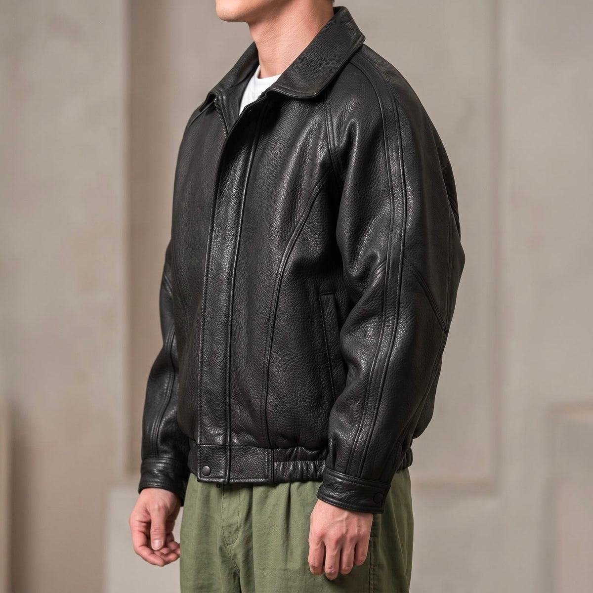 Side view of the black jacket on a model, showing raglan sleeves, seam detailing, elasticated hem and snap cuff. 2