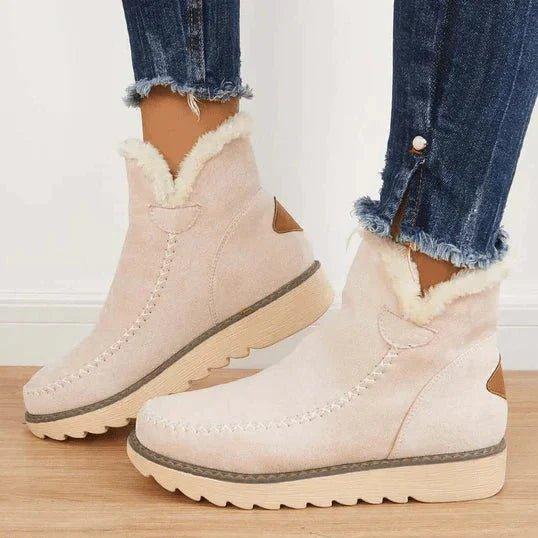 Beige ankle boots with soft fleece collar and cross-stitch detail, worn by a model in frayed jeans, side view. 3