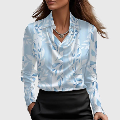 Model wears the satin blouse in a pale blue and white leaf print, with cowl neck, collar and black skirt. 5