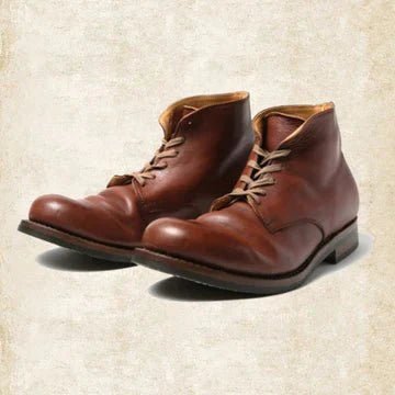 Pair of brown leather lace-up ankle boots with rounded toes and a thin dark sole, shown from the front on a textured cream background. 1