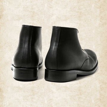Rear view of black leather boots, showing the stitched back seam, smooth heel counter and low stacked heel. 5