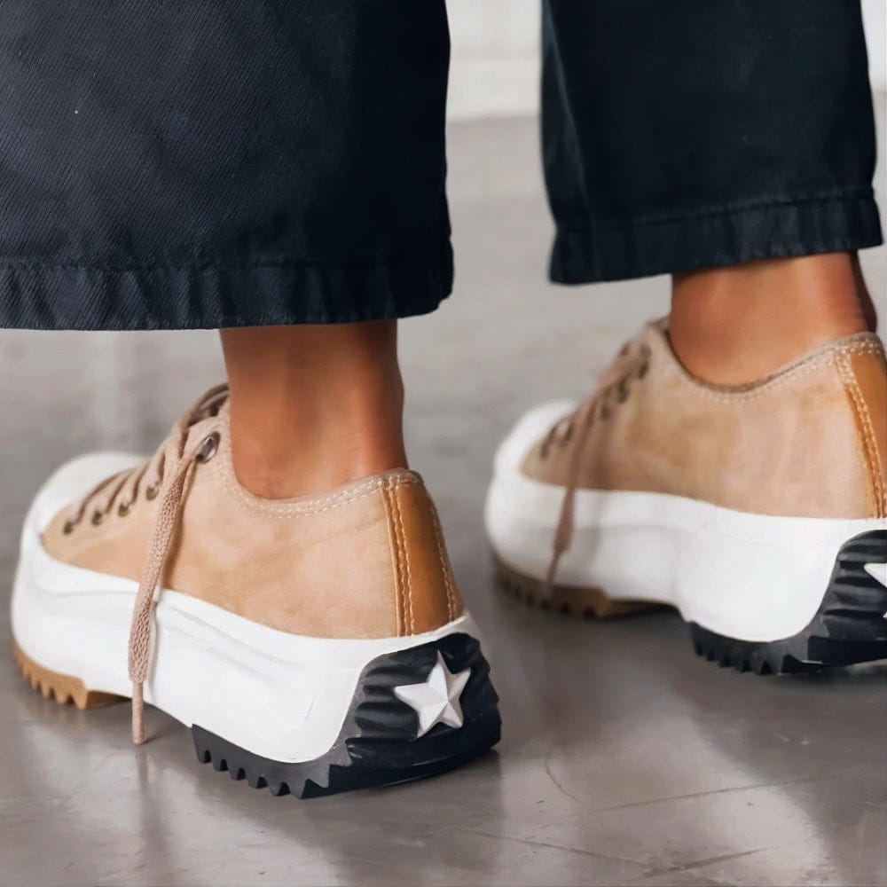Rear view of beige platform trainers on a model, showing the heel stitching and the star on the black tread. 2