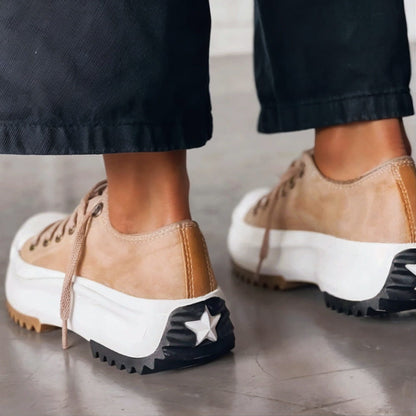 Rear view of beige platform trainers on a model, showing the heel stitching and the star on the black tread. 2