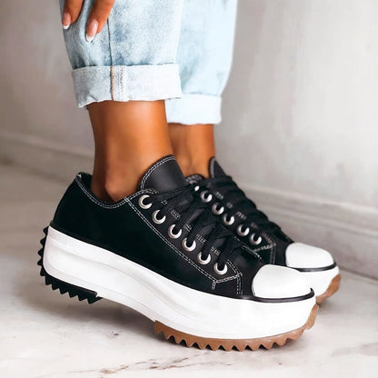 Black lace-up platform trainers with white contrast stitching, thick white midsole and gum outsole, worn with rolled-up light denim. 3
