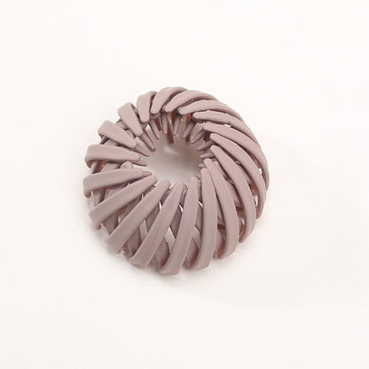 Single matte dusty mauve spiral bird's-nest clip on a plain pale background, shown from above and slightly to one side. 5
