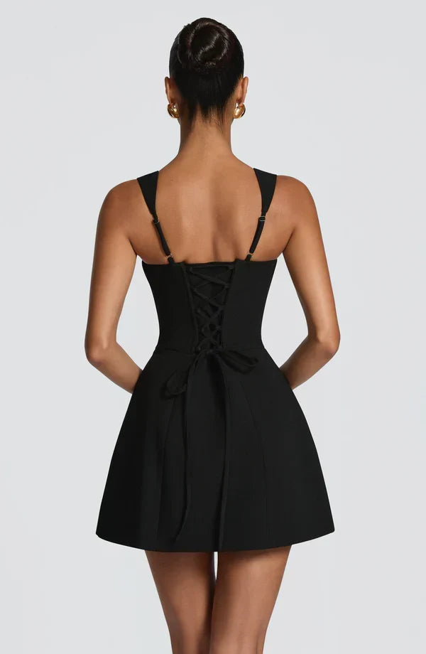 Back view of the black mini dress, showing the corset lacing with loose ties, adjustable straps and the flared skirt. 6