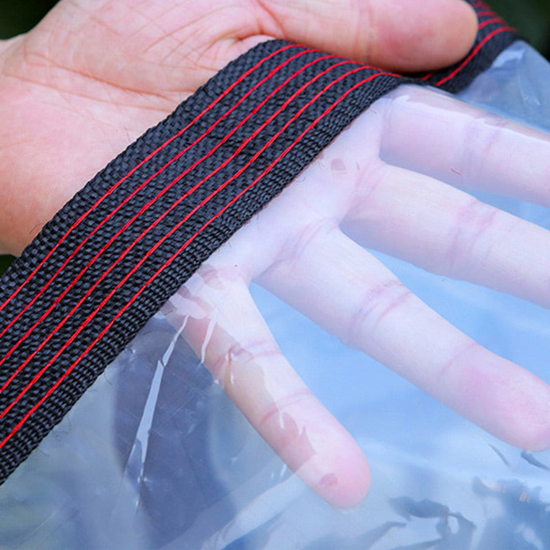Close-up of a hand pressed against the transparent sheet beside its black woven edge with red stitching, showing how see-through it is. 4