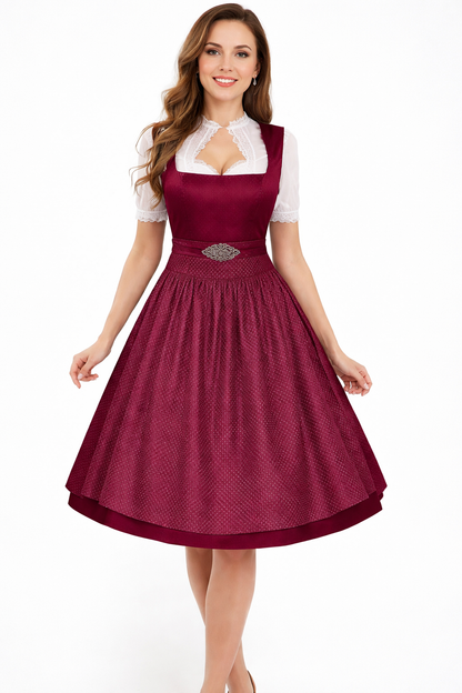 Smiling model in a burgundy dirndl with dotted textured apron, ornate clasp and white blouse with lace keyhole neckline and short sleeves. 4