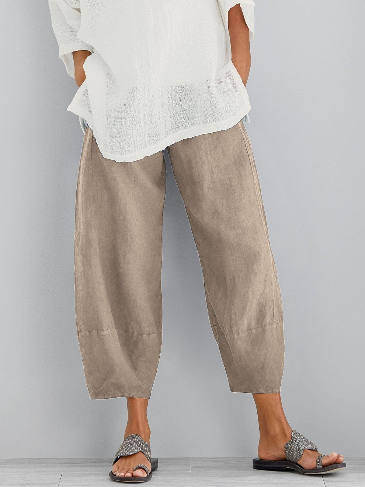 Beige cropped wide-leg trousers with a gathered waist, worn by a model with a sheer white top and studded sandals. 2