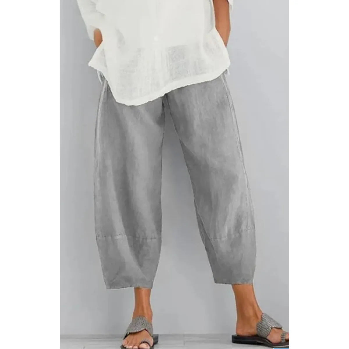 Light grey cropped wide-leg trousers with a gathered waist, worn with a loose white top and woven sandals. 4